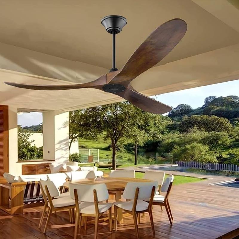 Modern outdoor dining area with wooden chairs and table under a covered patio, featuring a large wooden ceiling fan, surrounded by greenery and scenic views